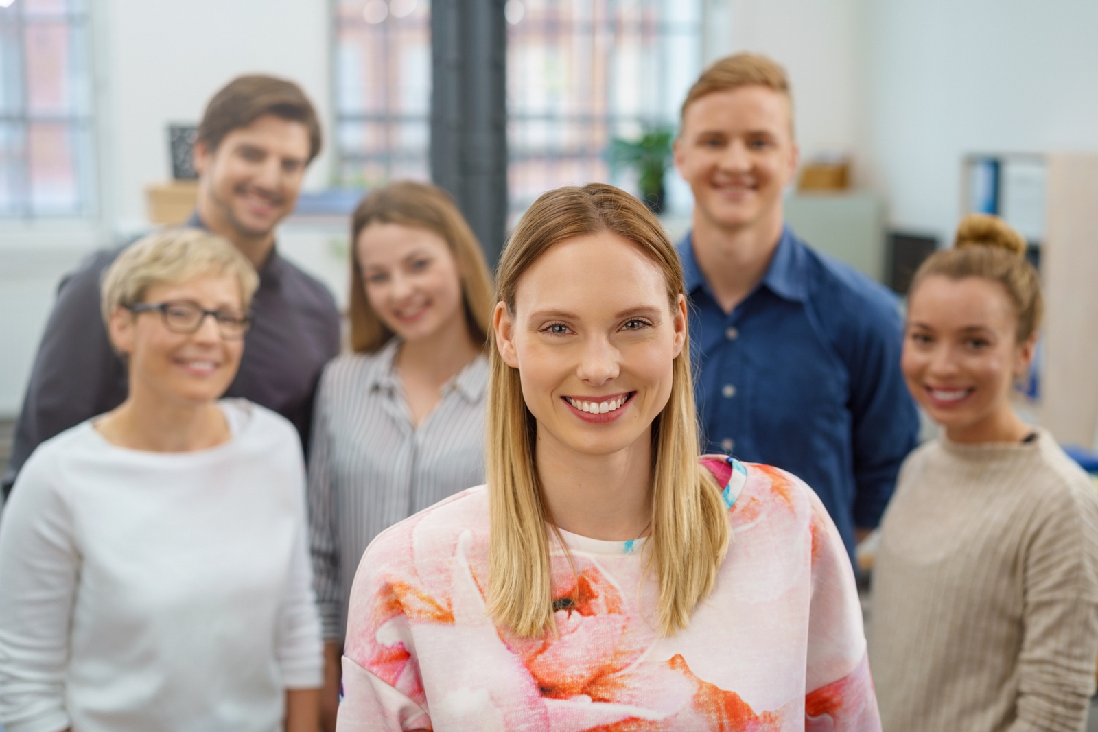 Eine junge Frau lächelt in die Kamera, im Hintergrund ist das team zu sehen.