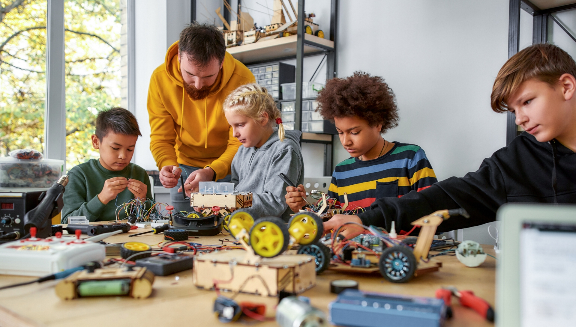 Vier Kinder mit einem Betreuer bei einer handwerklichen Bastelstunde